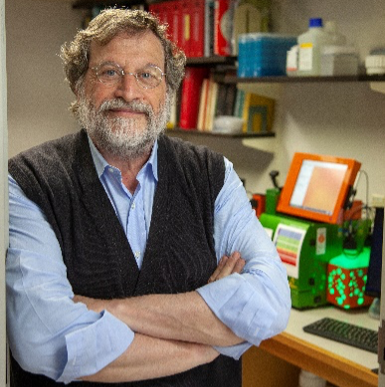 Jeffrey V. Ravetch stands with his arms crossed with lab equipment and books in the background.