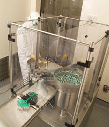 Laboratory setup showing the filling, stoppering, capping, and sealing process for ch14.18 antibody production inside a sterile enclosed chamber.