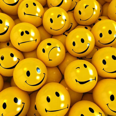 Pile of yellow smiley face balls with different facial expressions.