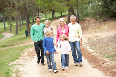 Three generations of family members walking together outdoors.