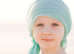 Portrait of a child wearing a light blue head covering, with a gentle smile looking directly at the camera.