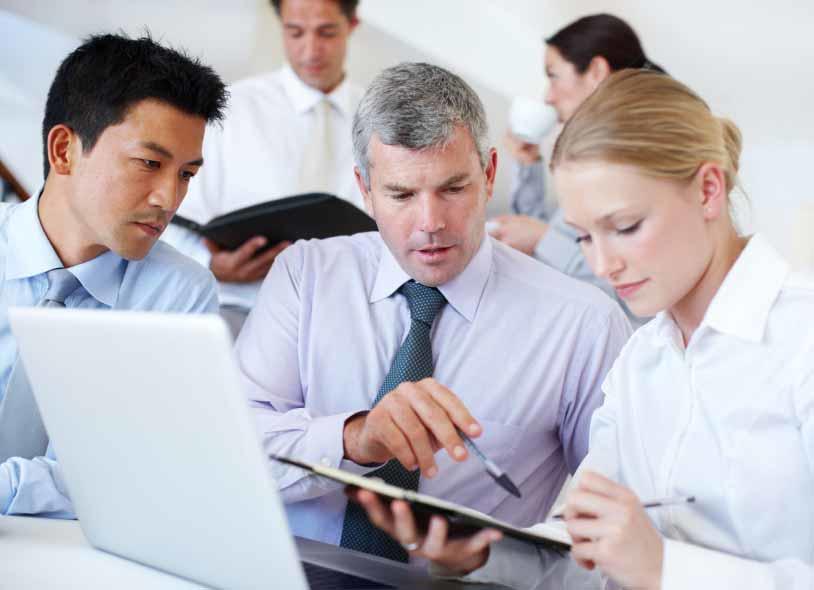 Two men and a woman talking while viewing a clipboard and sitting in front of a laptop