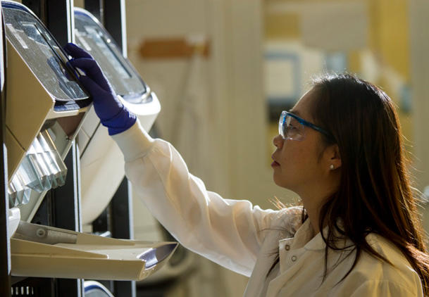 Researcher in a lab using a DNA sequencer. 