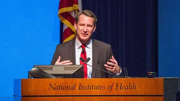 Dr. Norman Sharpless presenting from a podium at a town hall meeting in 2017.