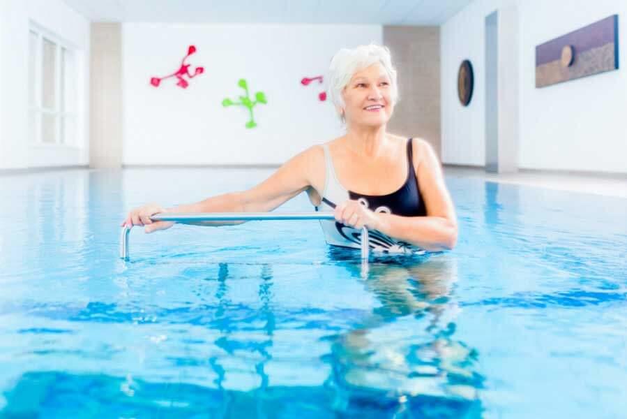 Woman with white hair doing water aerobics.