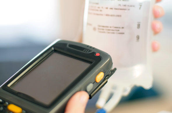 A handheld scanner being used to scan a barcode on an IV bag. 
