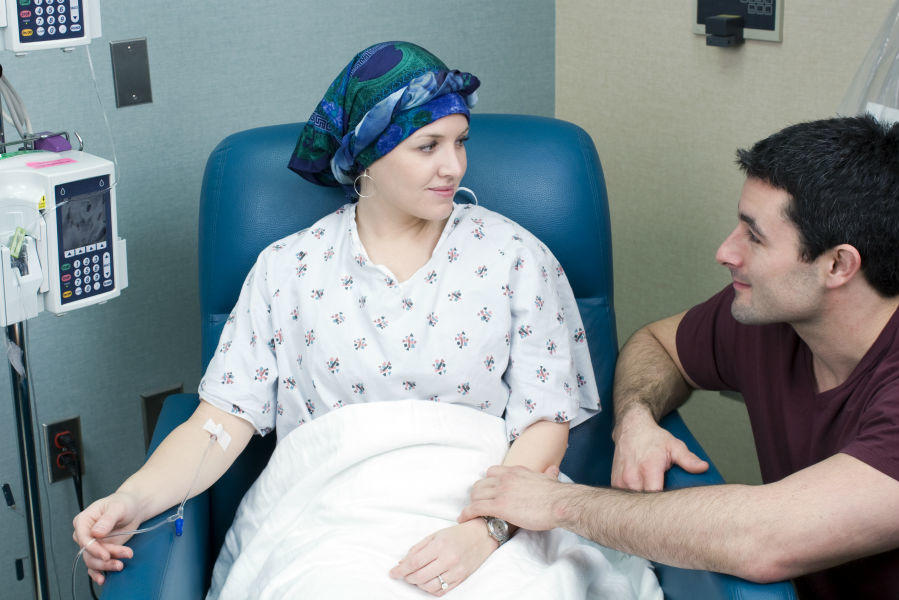 Woman getting chemo treatment supported by male friend