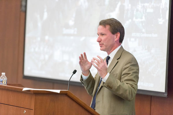 Dr. Norman E. Sharpless speaking at a podium.