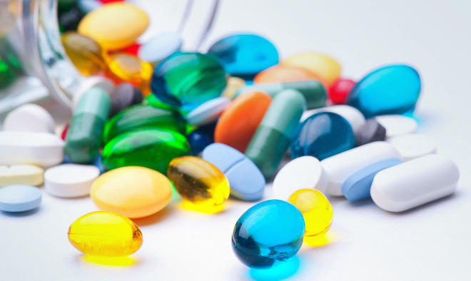 A close-up photo of various pills and capsules of varying shapes, sizes and colors. 