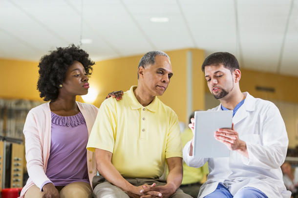 Older man with adult daughter talking to a doctor.