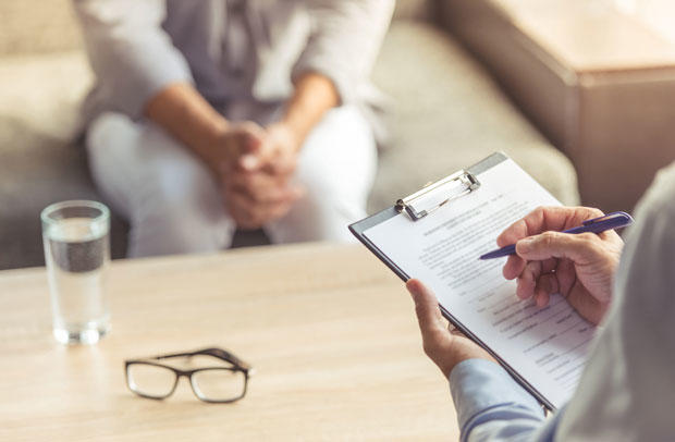 Doctor holding clipboard while interviewing a patient.
