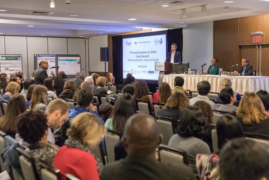 Attendees watching a presentation at the symposium.