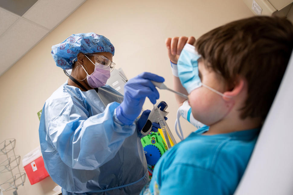 A nurse at St. Jude checking a boy's temperature.