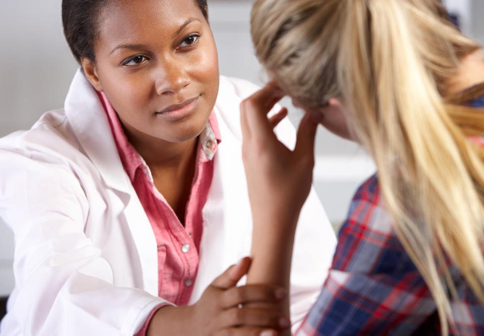 Female doctor with sympathetic expression listens to a young female patient.