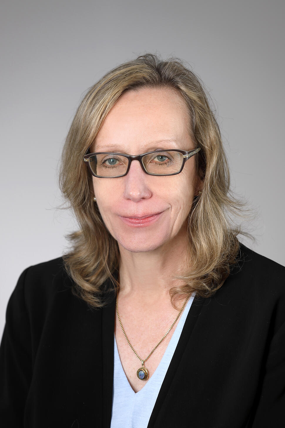 Headshot of Dr. Brigitte Widemann with shoulder-length blond hair and rectangular glasses, smiling slightly at the camera.
