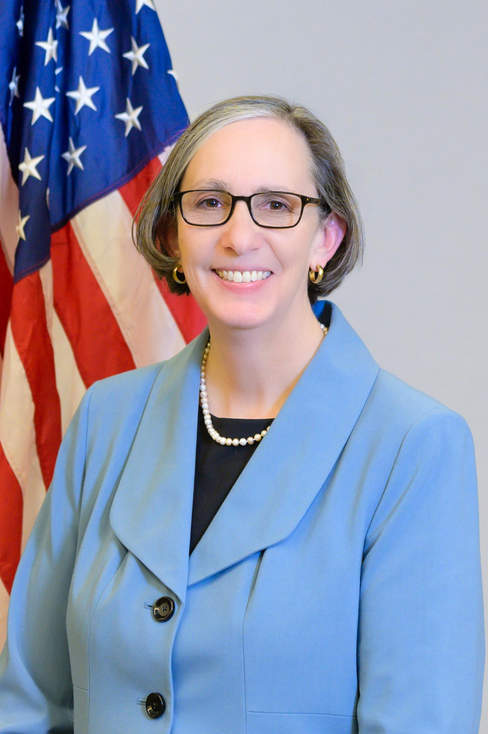 NCI Director Dr. Rathmell stands in front of the U.S. flag