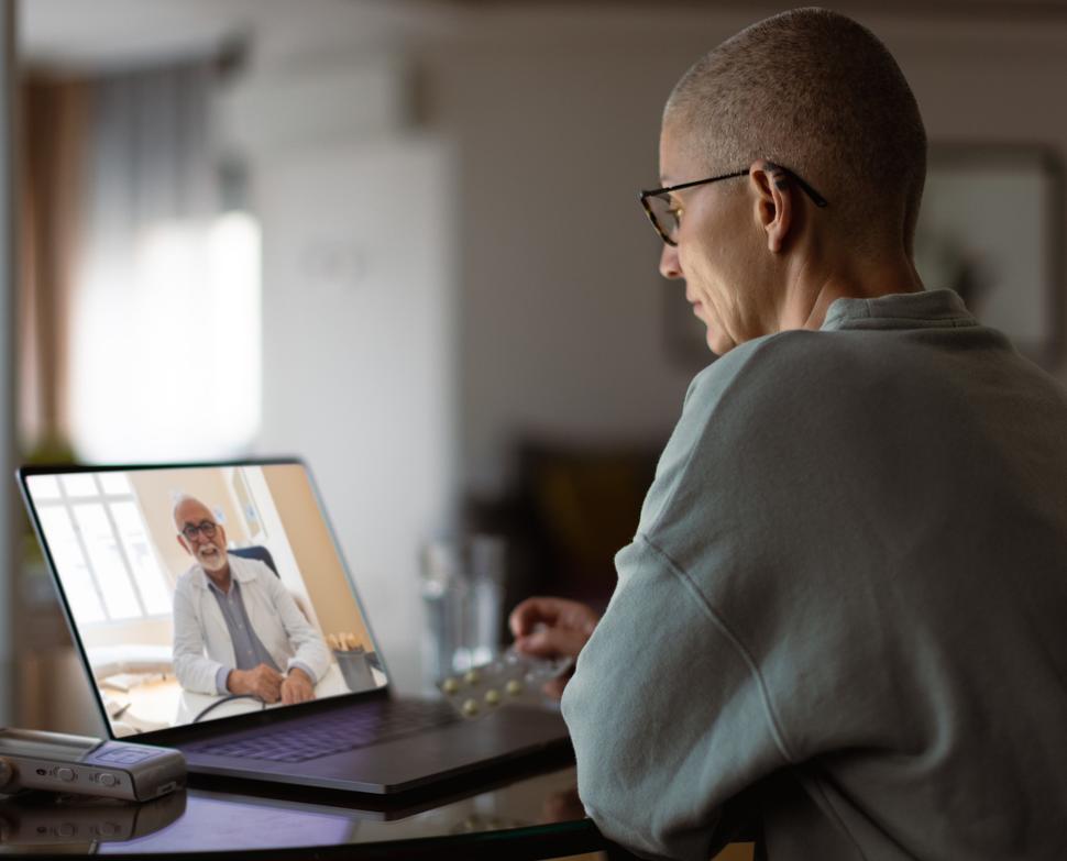 Middle-aged woman with cancer having a virtual appointment with doctor on the computer.