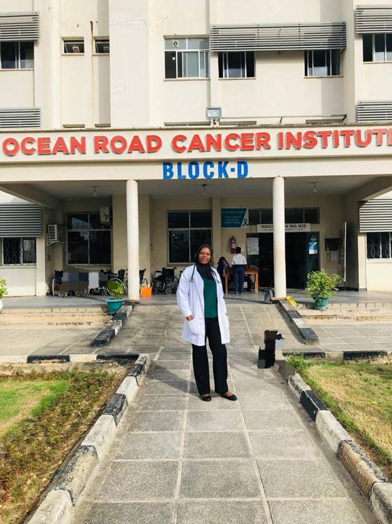 Dr. Marriam Mponda standing in front of the oncology teaching hospital at Muhimbili University in Tanzania.