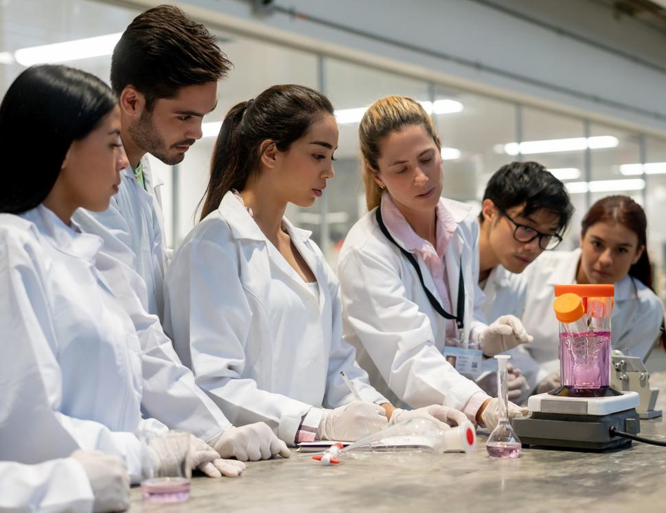 An image of a female researcher in the lab with several students to her left and right.