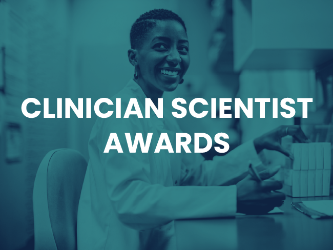 smiling chemist working at a desk, white text reading "Clinician Scientist Awards"