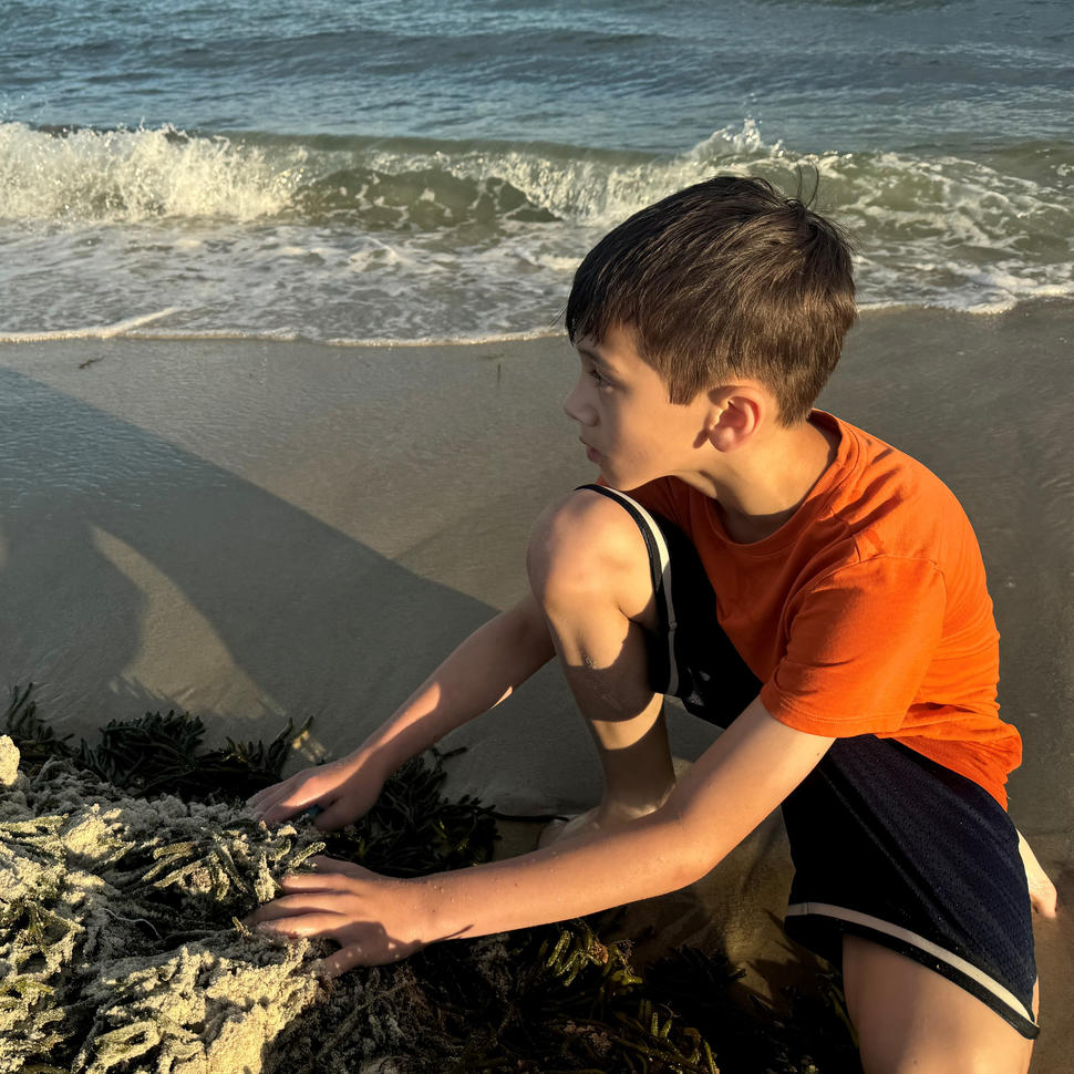 Charlie, wearing orange t-shirt and black shorts, at the beach.