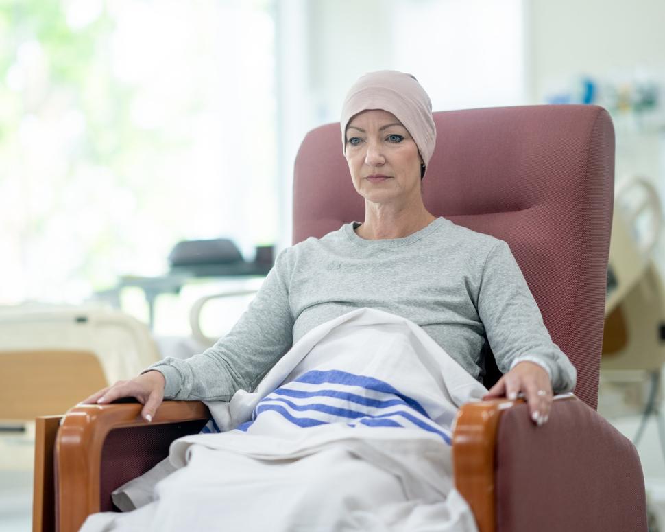 A middle-aged woman in a reclining chair receiving chemotherapy