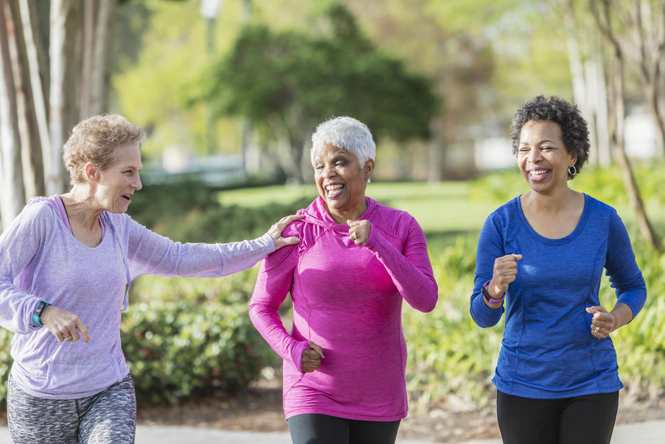 Three senior women going for a walk with one woman touching the shoulder of another woman.