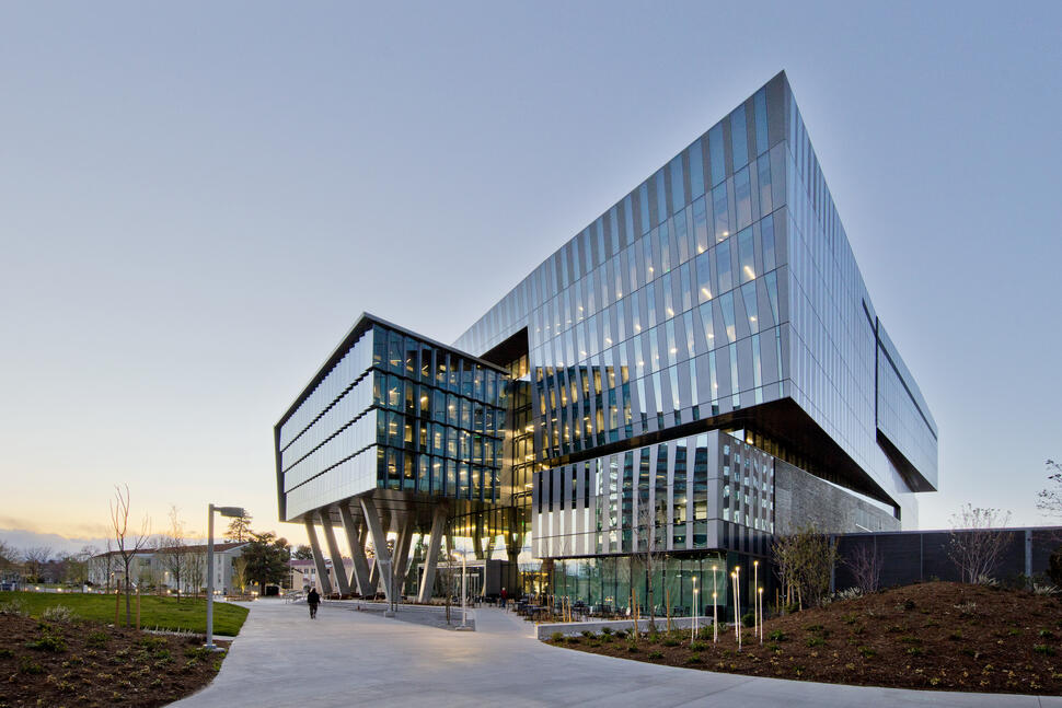 University of Colorado Cancer Center, a modern glass building with angular cantilevered sections and lit interiors at dusk.