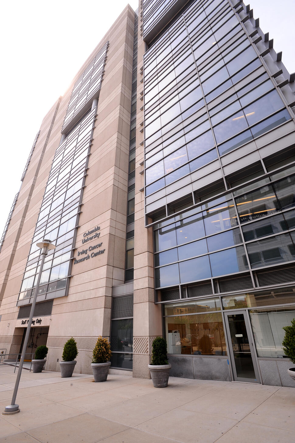 Columbia University Herbert Irving Cancer Center building with glass and stone facade, viewed from street level with signage visible.