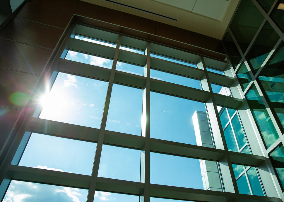 Sunlight streams through tall grid windows inside Georgetown Lombardi Comprehensive Cancer Center, with blue sky visible outside.