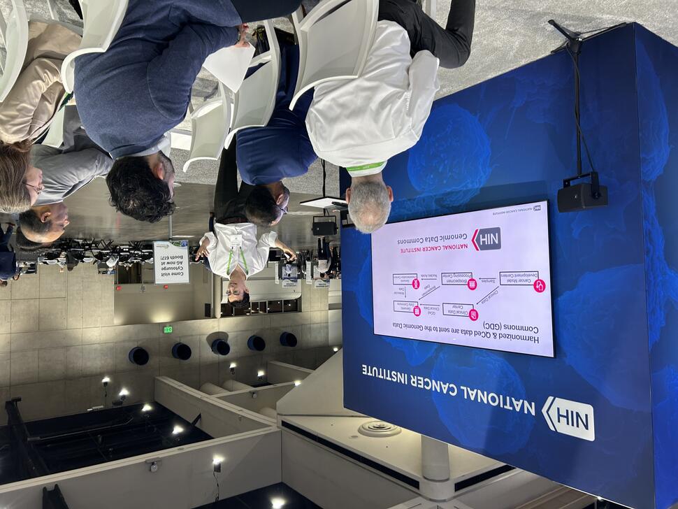 Photo of Dr. Justin Benavidez giving a presentation to a group of people at the NCI Exhibit Booth