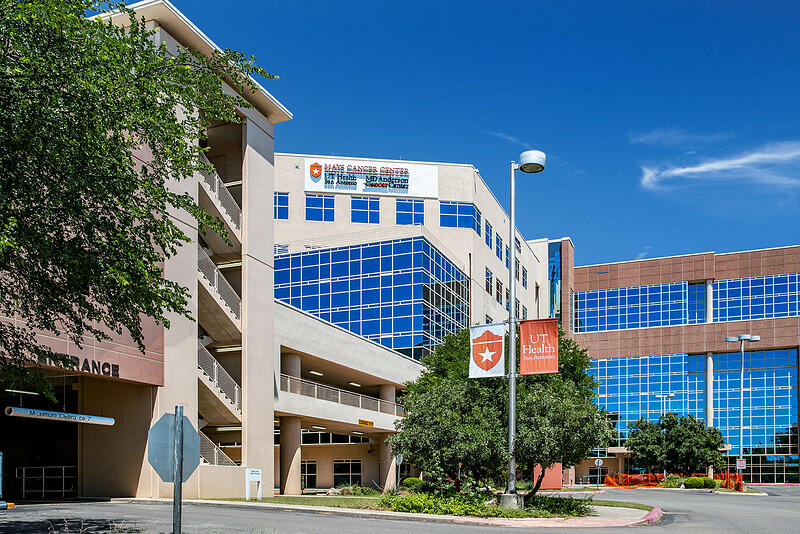 Mays Cancer Center at UT Health San Antonio, a multi-building complex with glass windows, signage, and street-level view.