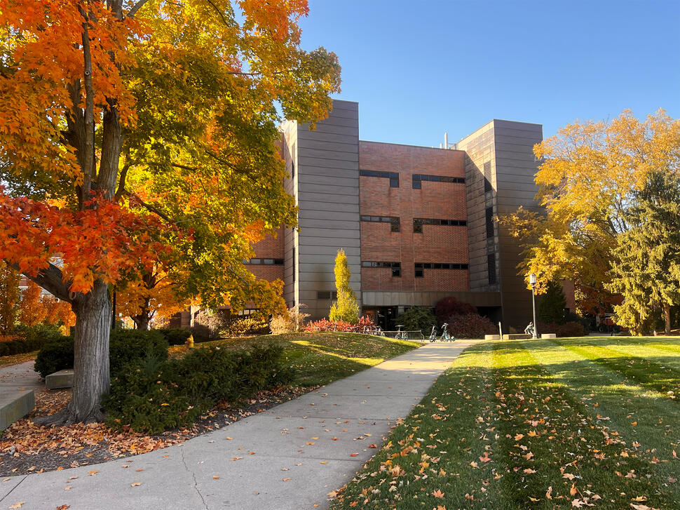 Purdue University Institute for Cancer Research building surrounded by autumn trees, with a walkway leading to the entrance.