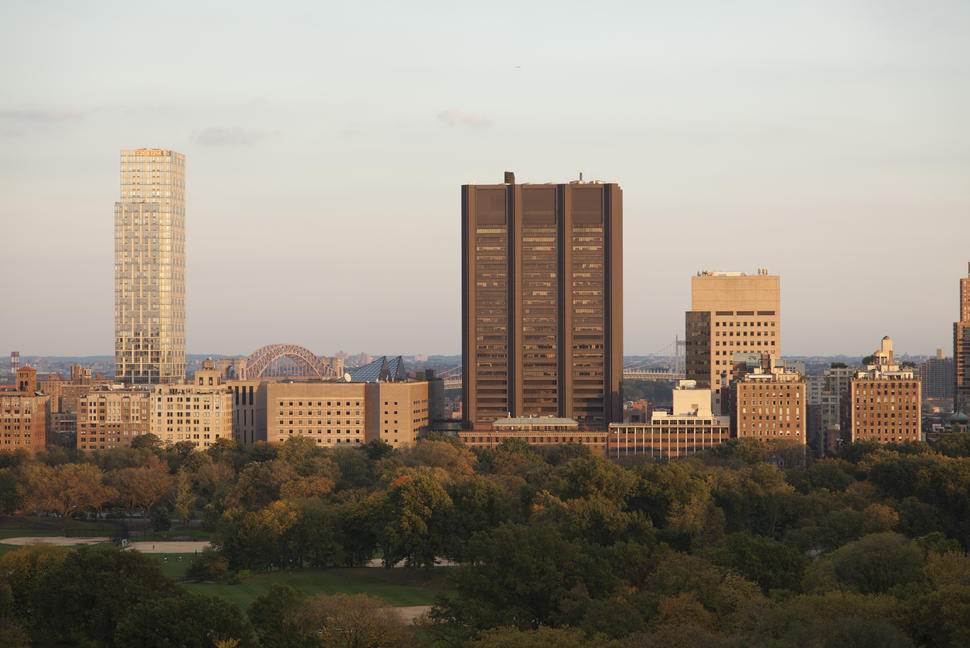 The Tisch Cancer Institute at Mount Sinai near a large park with city buildings and distant bridges at sunset.