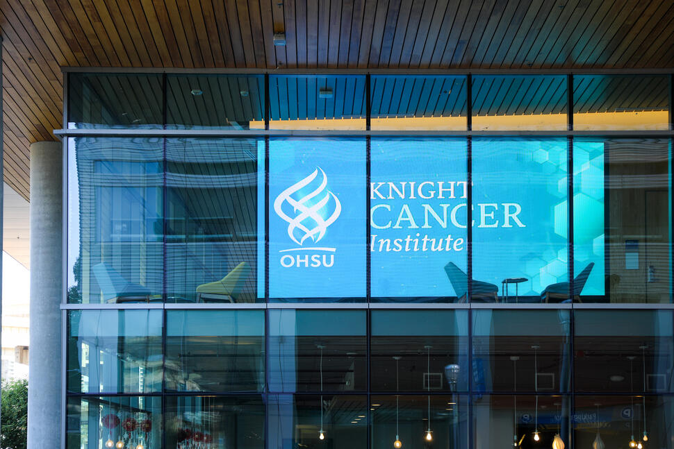 OHSU Knight Cancer Institute logo displayed on a large glass window, with interior seating visible behind it.