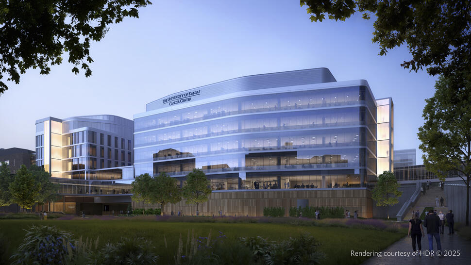 University of Kansas Cancer Center, a large modern glass building surrounded by trees, landscaped grounds, and walkways at dusk.