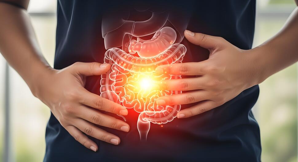 Medical illustration of the digestive tract with inflamed intestines highlighted in red and yellow over a person's abdomen.
