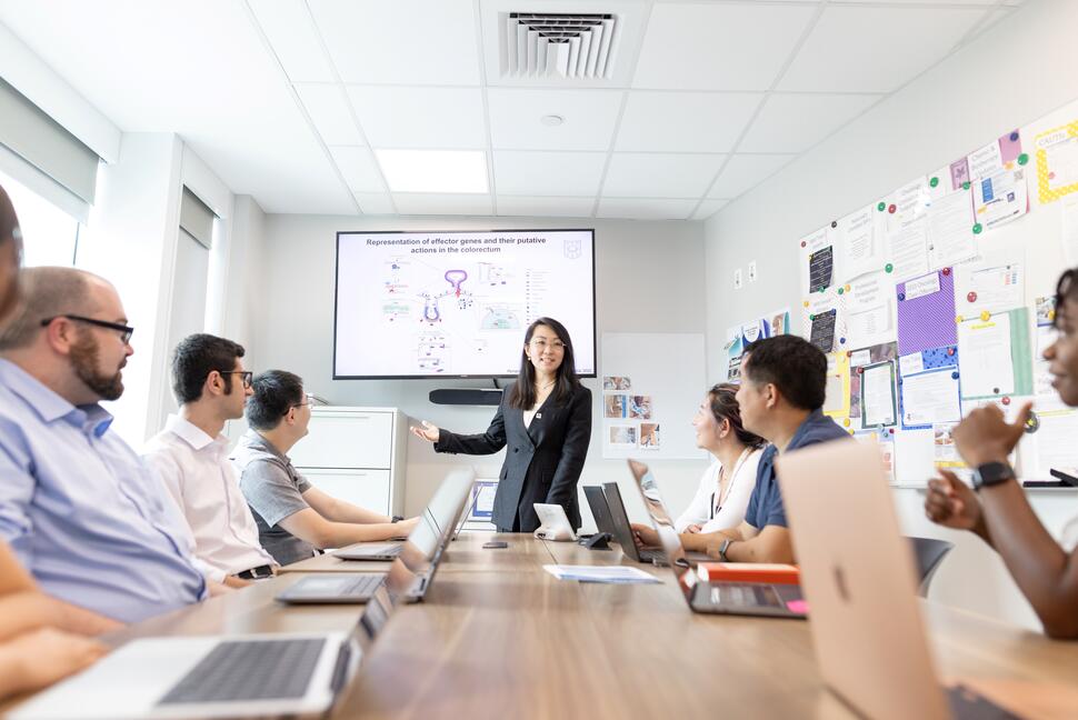 A researcher presents scientific findings to colleagues during a team meeting.