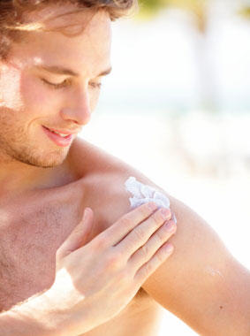 Young male applying sunscreen