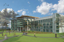 External view of the University of Hawaii Cancer Center which is a modern building with large glass windows is set in a lush, green landscape.