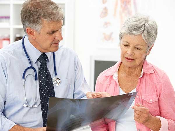 Male doctor and female patient look at a digital image the doctor holds.