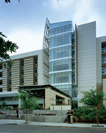 External view of the Beckman Research Institute City of Hope Comprehensive Cancer Center. It has  contemporary building features a striking glass facade in the center, flanked by modern concrete elements.