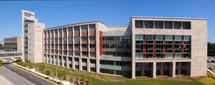 External view of Indiana University Melvin and Bren Simon Cancer Center, a large modern building with a facade of glass and concrete, featuring multiple floors and large windows. 
