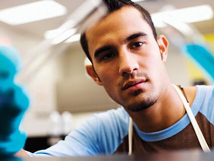 Male technician examining a vial.