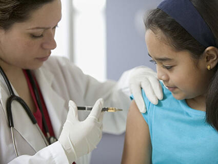 Doctor administering vaccination to young girl