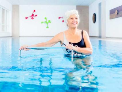 Woman with white hair doing water aerobics.