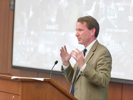Dr. Norman E. Sharpless speaking at a podium.