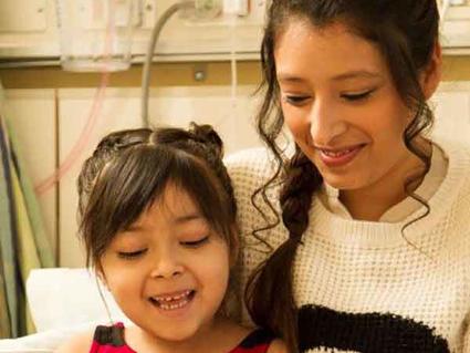 Two sisters sitting side by side reading in a hospital bed