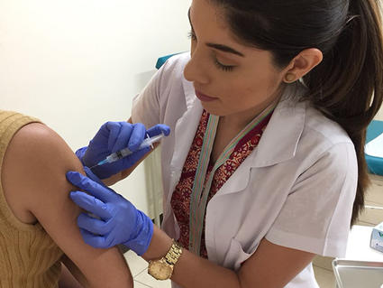A nurse administering an HPV vaccine to a young woman.
