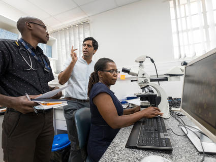 Dr. Satish Gopal in discussions with two office staff during his previous job in Malawi in Sub-Saharan Africa.